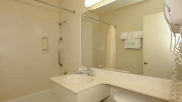 A bathroom with a sink, mirror, shower, and hairdryer.