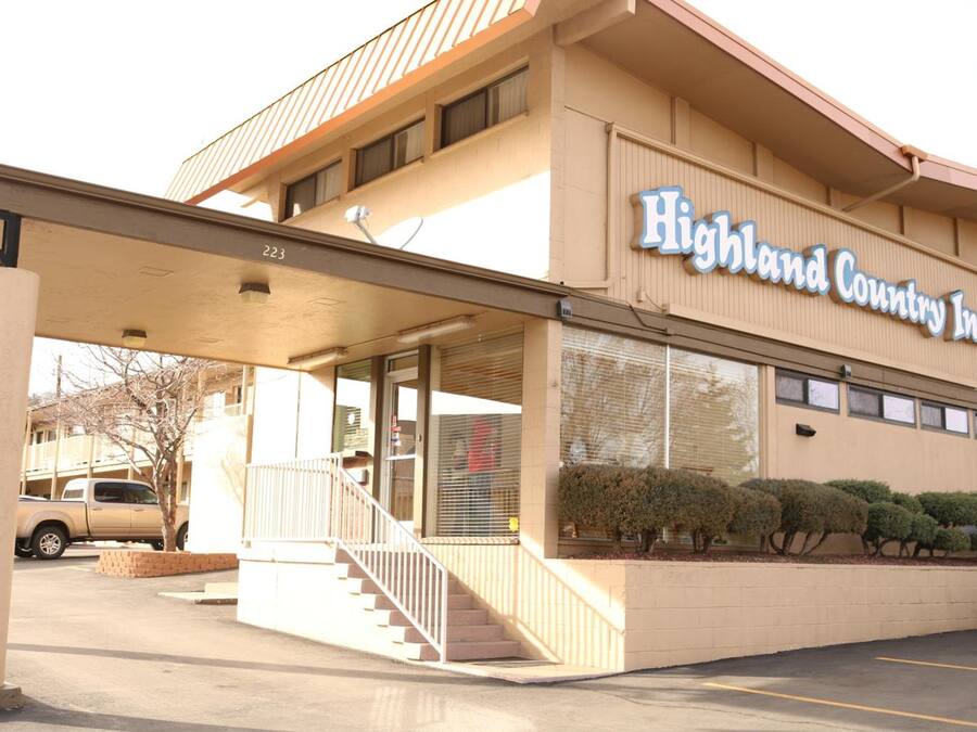 Highland Country Inn with a covered entrance, a staircase, and a parking lot.