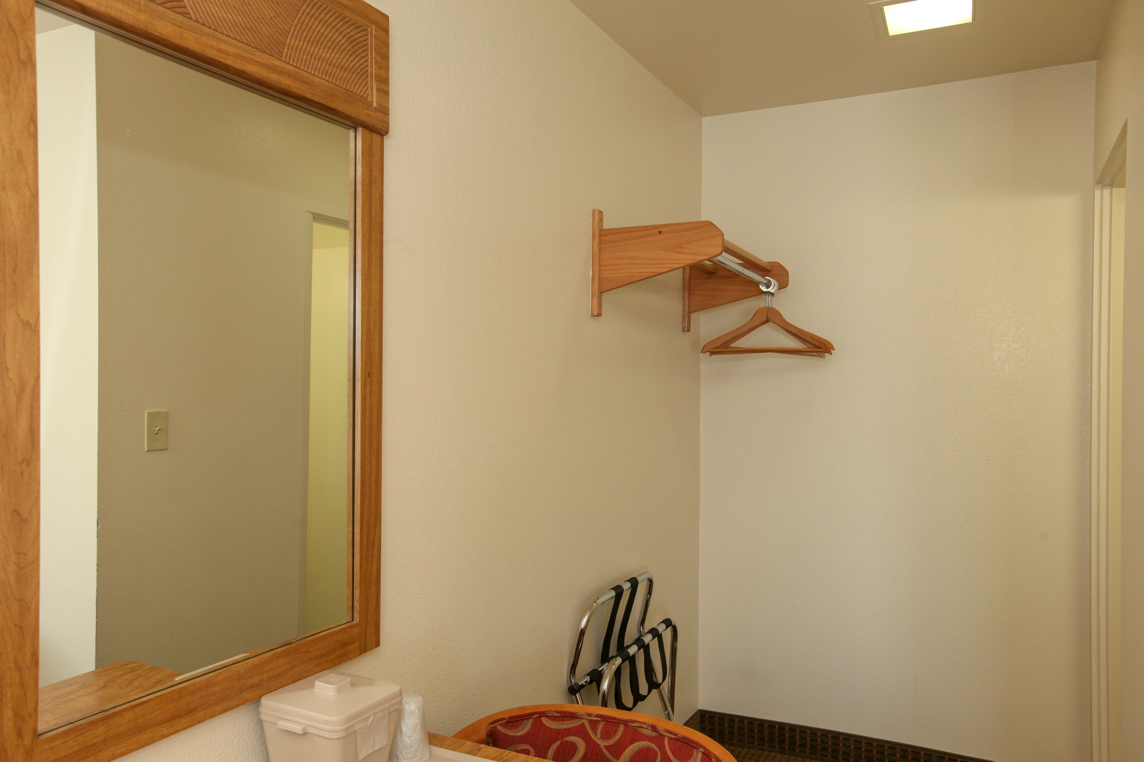 A bathroom with a large mirror, wooden towel rack, and a chair.