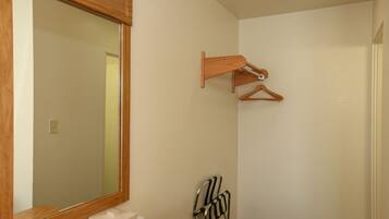 A bathroom with a large mirror, wooden towel rack, and a chair.