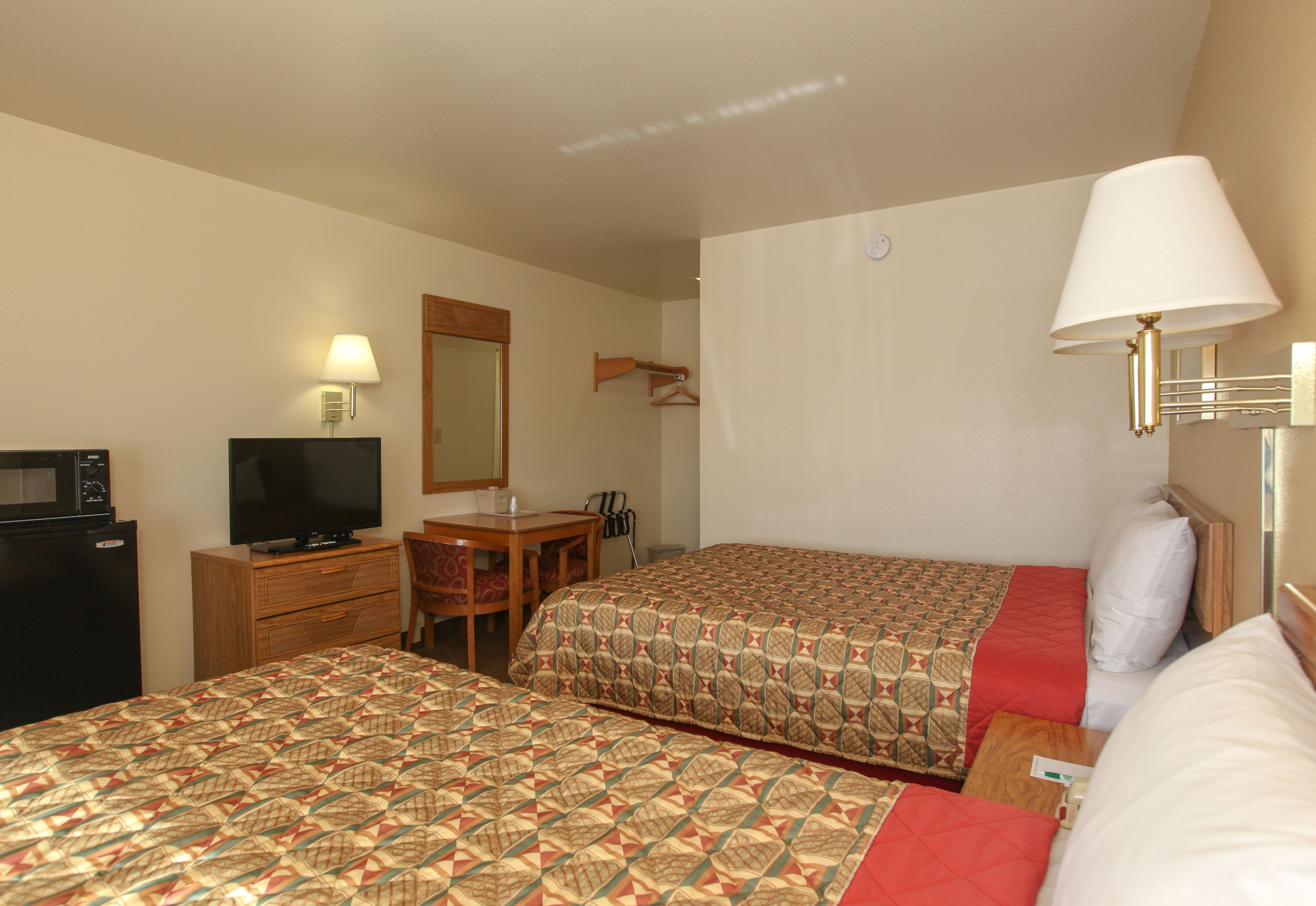 Una habitación de hotel con dos camas, un escritorio, un televisor y un microondas.