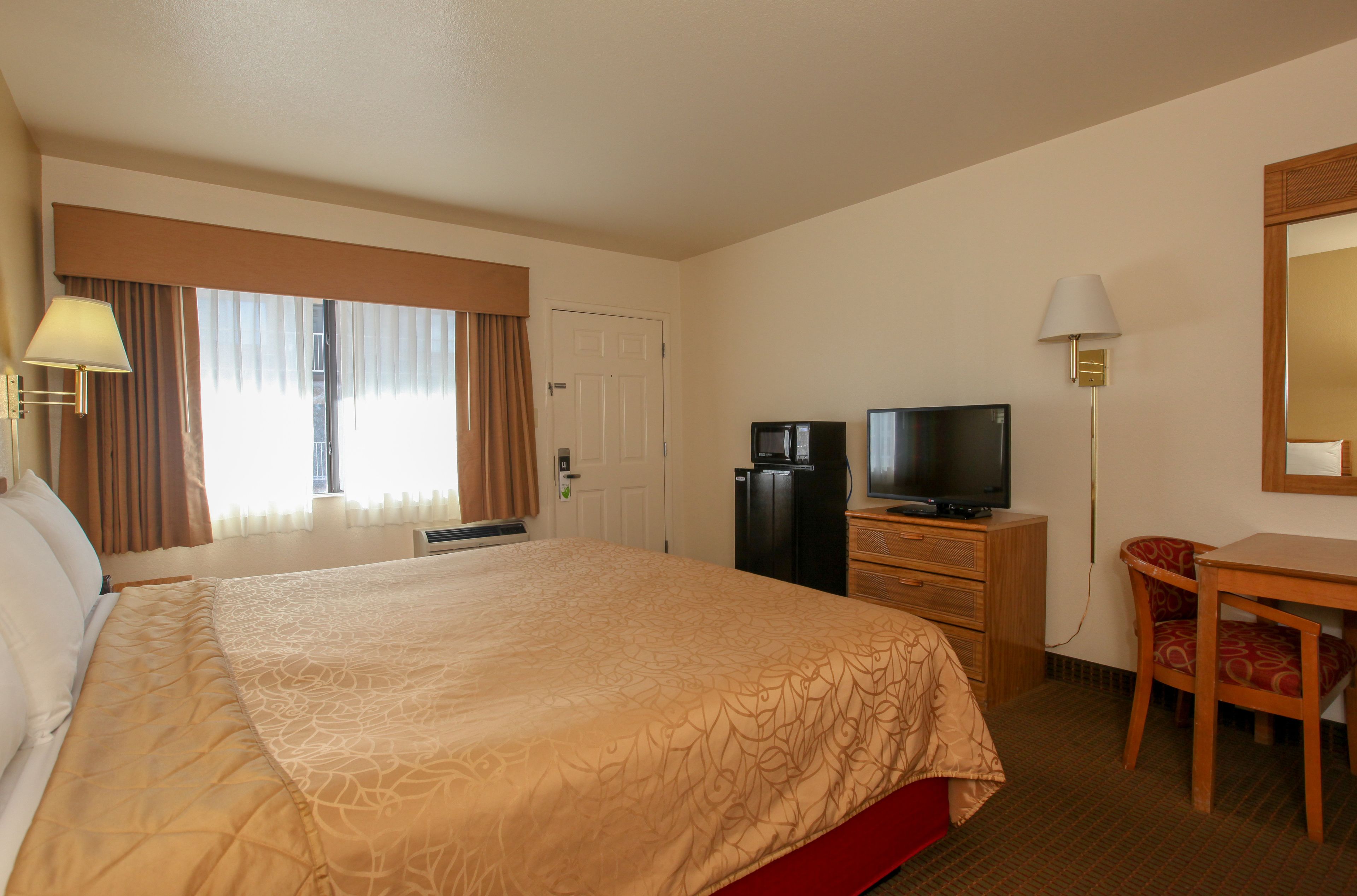Une chambre d’hôtel avec un grand lit, une télévision, un bureau et une chaise.