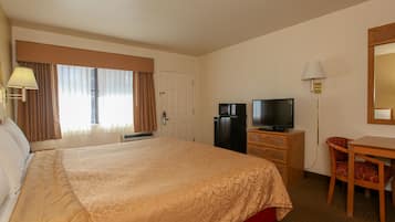 Une chambre d’hôtel avec un grand lit, une télévision, un bureau et une chaise.