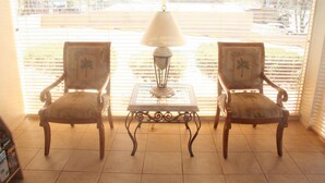 Two armchairs with a table and a lamp in a room with a large window. - Highland Country Inn (Flagstaff)