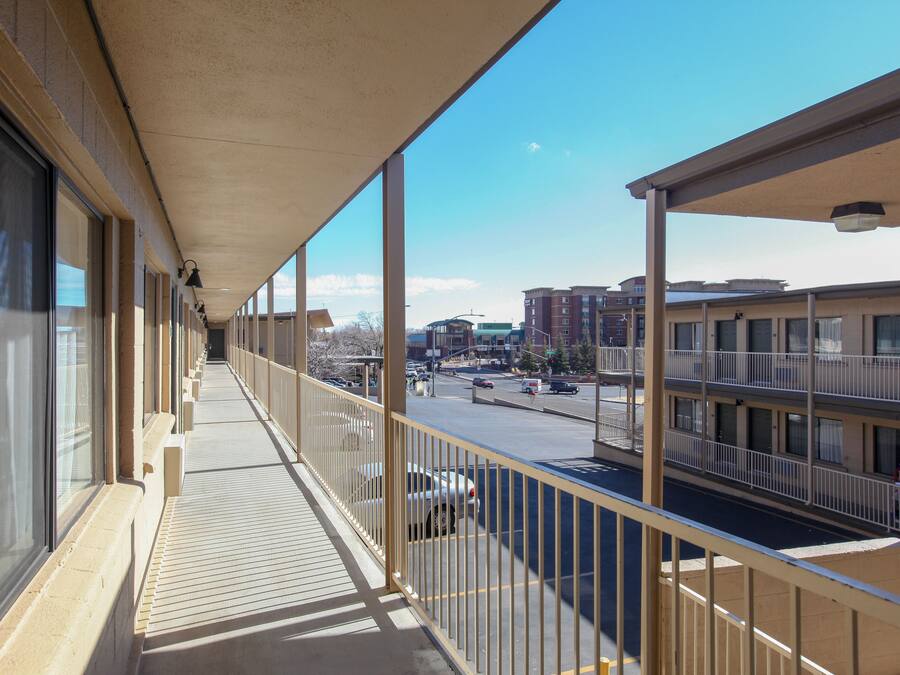 A balcony with a view of a city street, large windows, and a building with multiple floors.