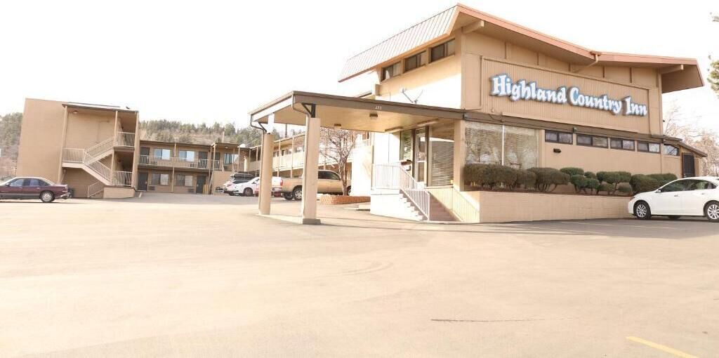 Ein Motel mit überdachtem Parkplatz und einem zweistöckigen Gebäude.