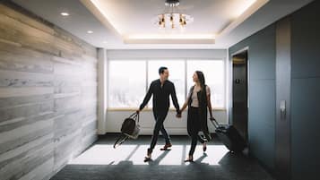 A modern hotel lobby with a large window, a chandelier, and an elevator.