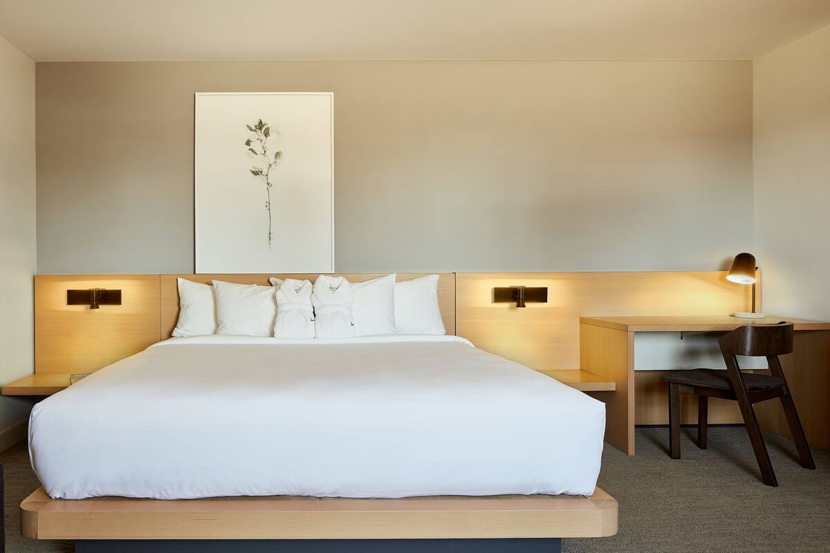 A hotel room with a large bed, a desk, and a chair.