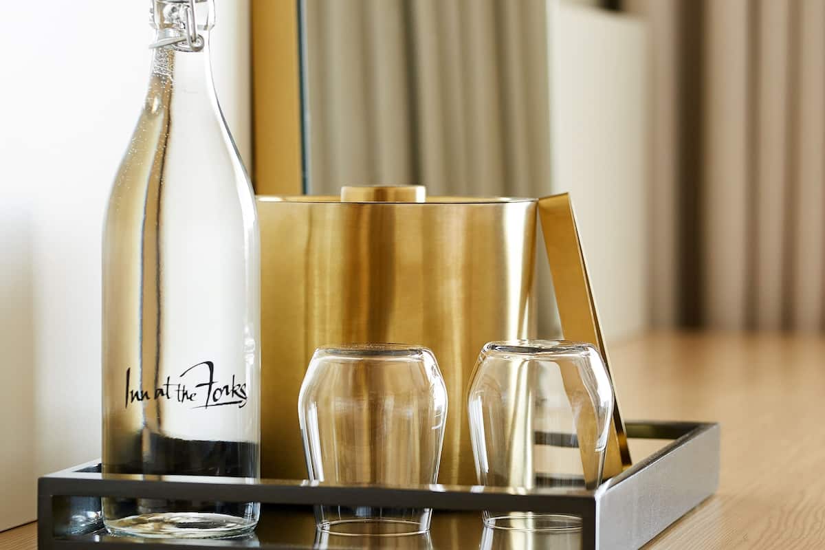 A bottle of wine, two glasses, and a tray on a wooden table.
