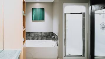 Un baño moderno con bañera, cabina de ducha de vidrio y un cuadro abstracto verde en la pared.