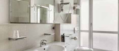 A modern bathroom with a large mirror, a sink, a toilet, and a bidet.