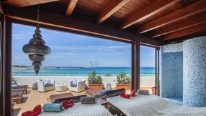 Een kamer met twee bedden, uitzicht op zee en een balkon met zitplaatsen.