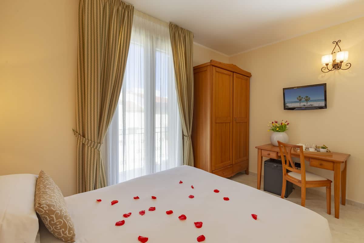 Een hotelkamer met een bed, een bureau, een kledingkast en een schilderij aan de muur.