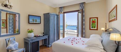 A hotel room with a bed, a desk, a chair, and a view of the sea.