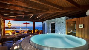 Een hottub met uitzicht op zee, houten balken in het plafond en een sauna.