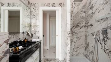 A bathroom with a marble wall, a black vanity, a shower, and a mirror.