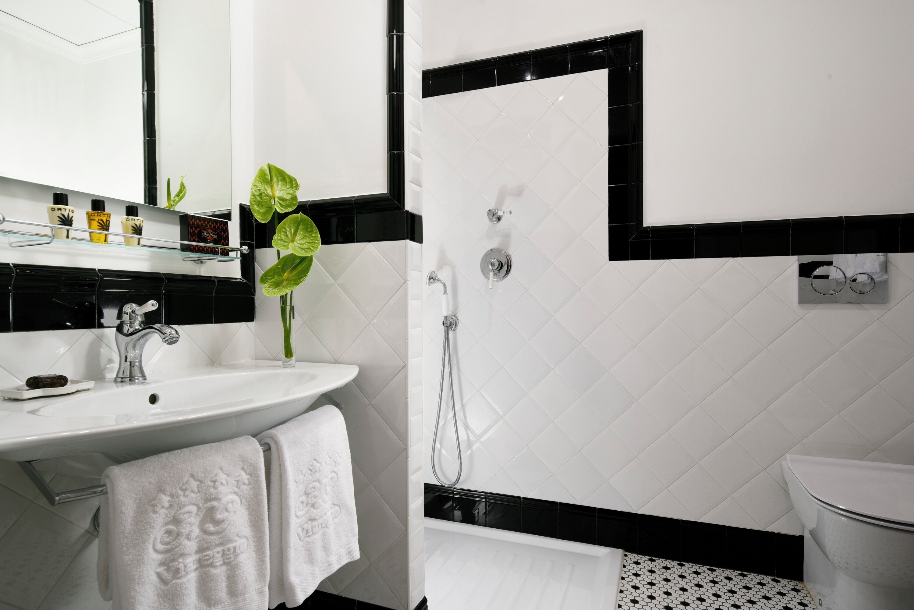 Une salle de bain moderne avec un lavabo blanc, un miroir, une douche et des toilettes.
