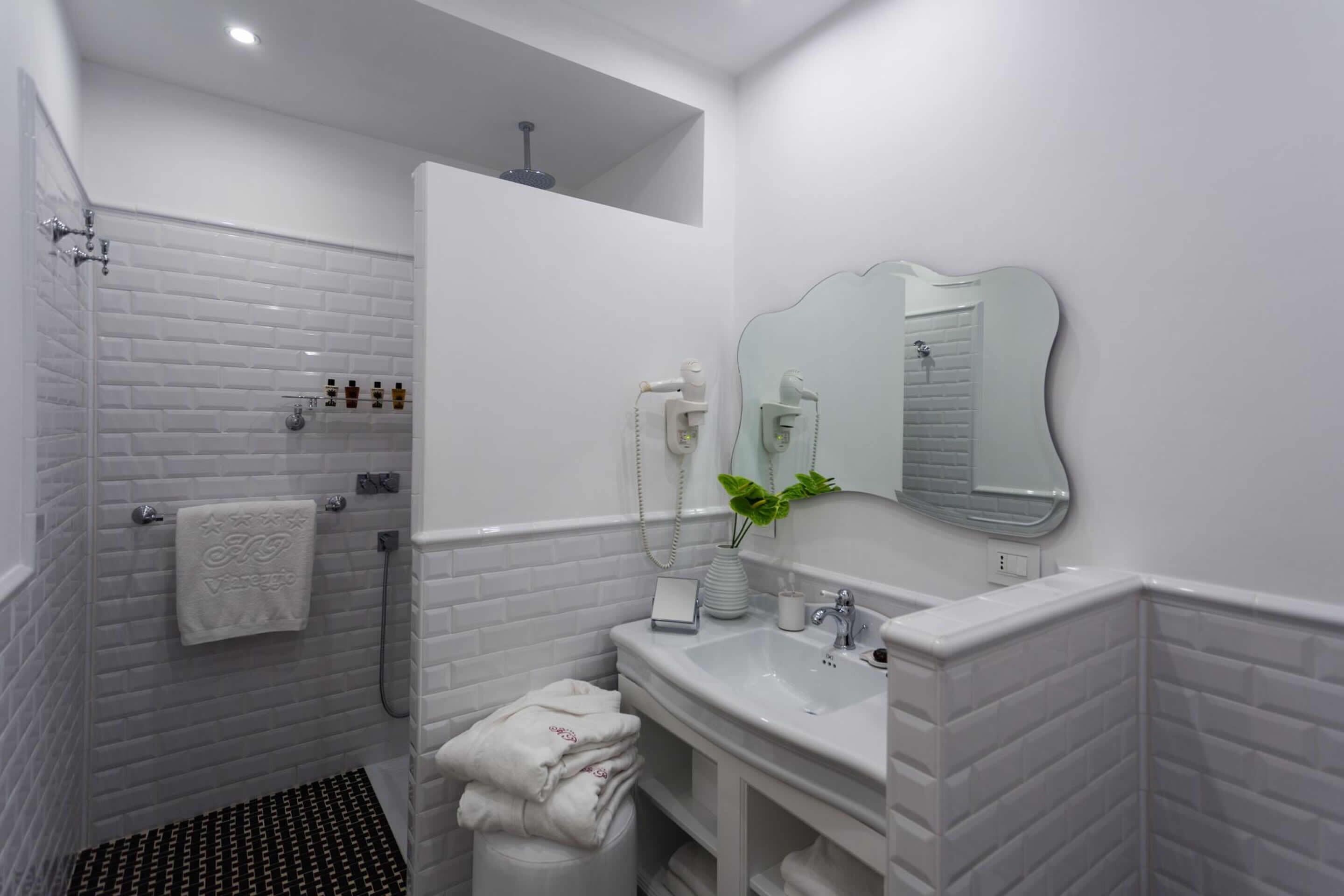 A modern bathroom with white subway tiles, a shower, a sink, and a mirror.