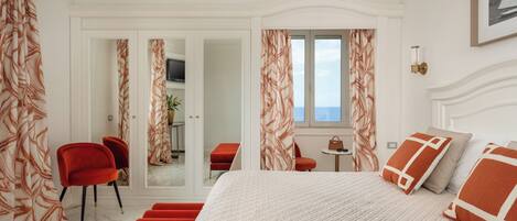 A bedroom with a bed, red chairs, a small table, and a view through a door.