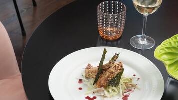 Ein Esstisch mit einem weißen Teller Essen, einem Glas Weißwein und einem klaren Glas.