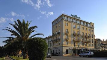 Un hotel a più piani con balconi, cielo sereno e palme.