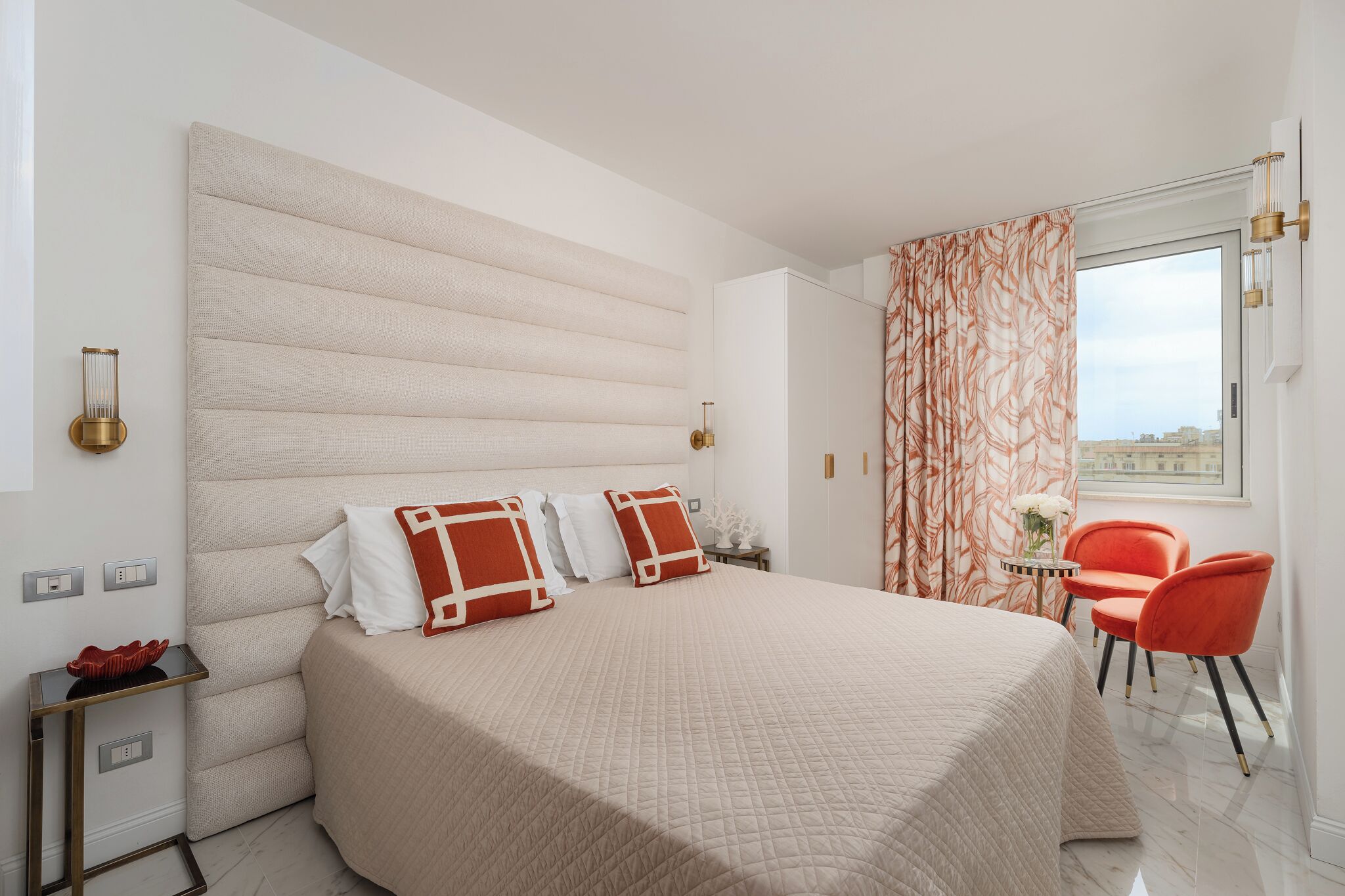 A hotel room with a large bed, a small table with chairs, and a window with curtains.