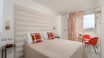 A hotel room with a large bed, a small table with chairs, and a window with curtains.
