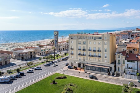 A coastal town with a prominent clock tower, a hotel named 'The President,' and a beach in the background.. Hotel President Viareggio
