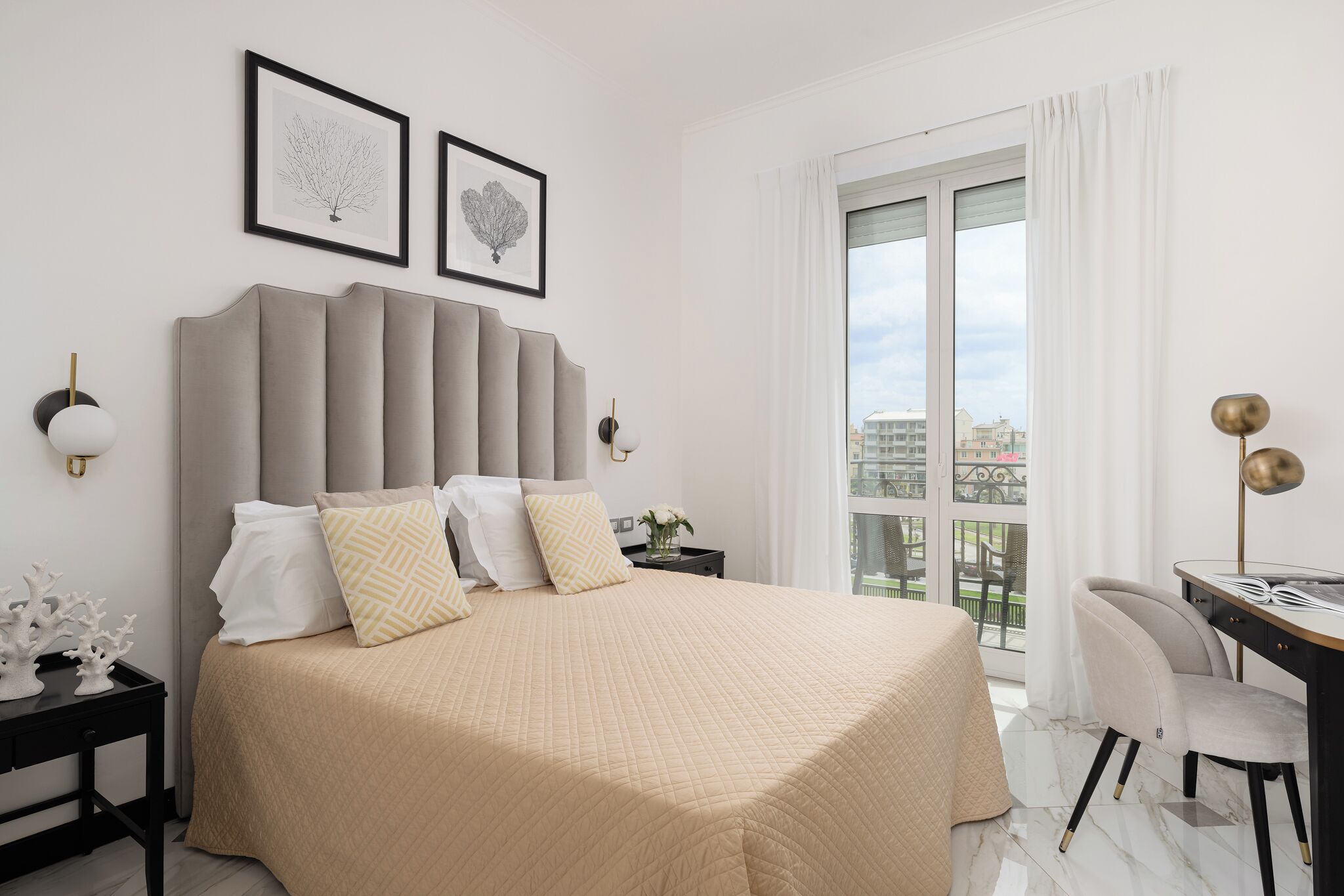 A modern bedroom with a large bed, a desk, and a view of the city.