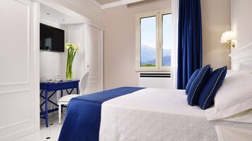 Una camera d'hotel con un letto, una scrivania e una finestra vista montagne.
