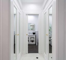 Un pasillo estrecho con puertas blancas que dan a un baño.