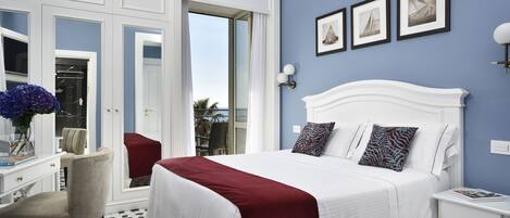 Habitación de hotel con una cama grande, un escritorio y una silla. Hay tres cuadros en la pared.