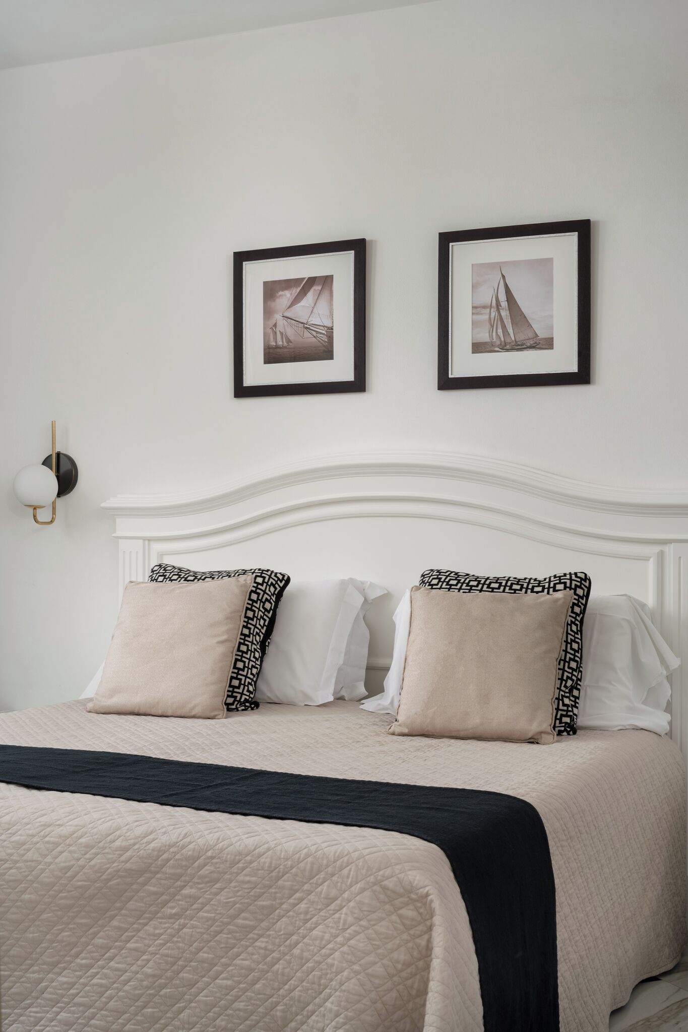 A neatly arranged bed with a quilted bedspread, two pillows, and a black throw blanket.