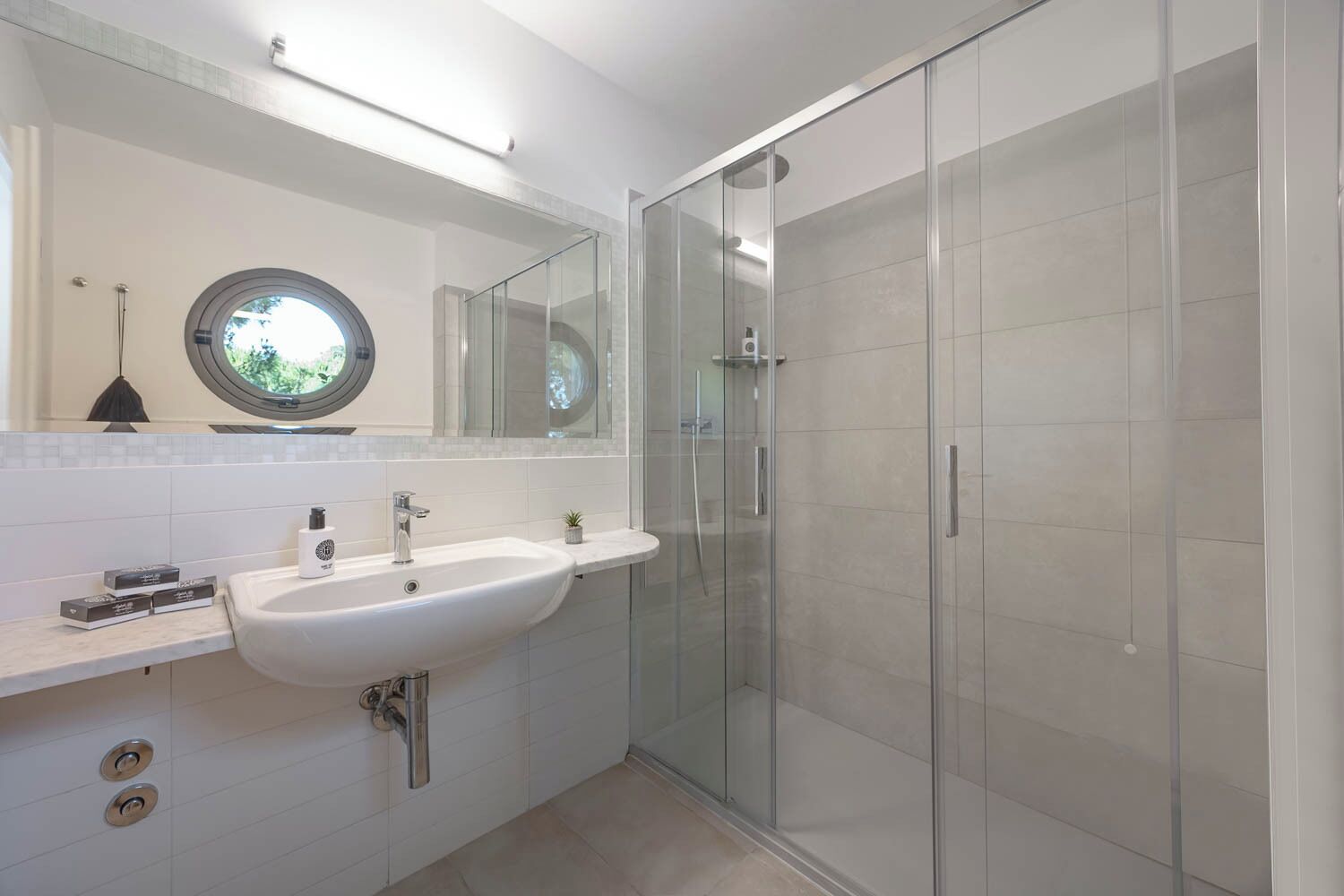 Un bany modern amb un lavabo, un mirall i una cabina de dutxa de vidre.