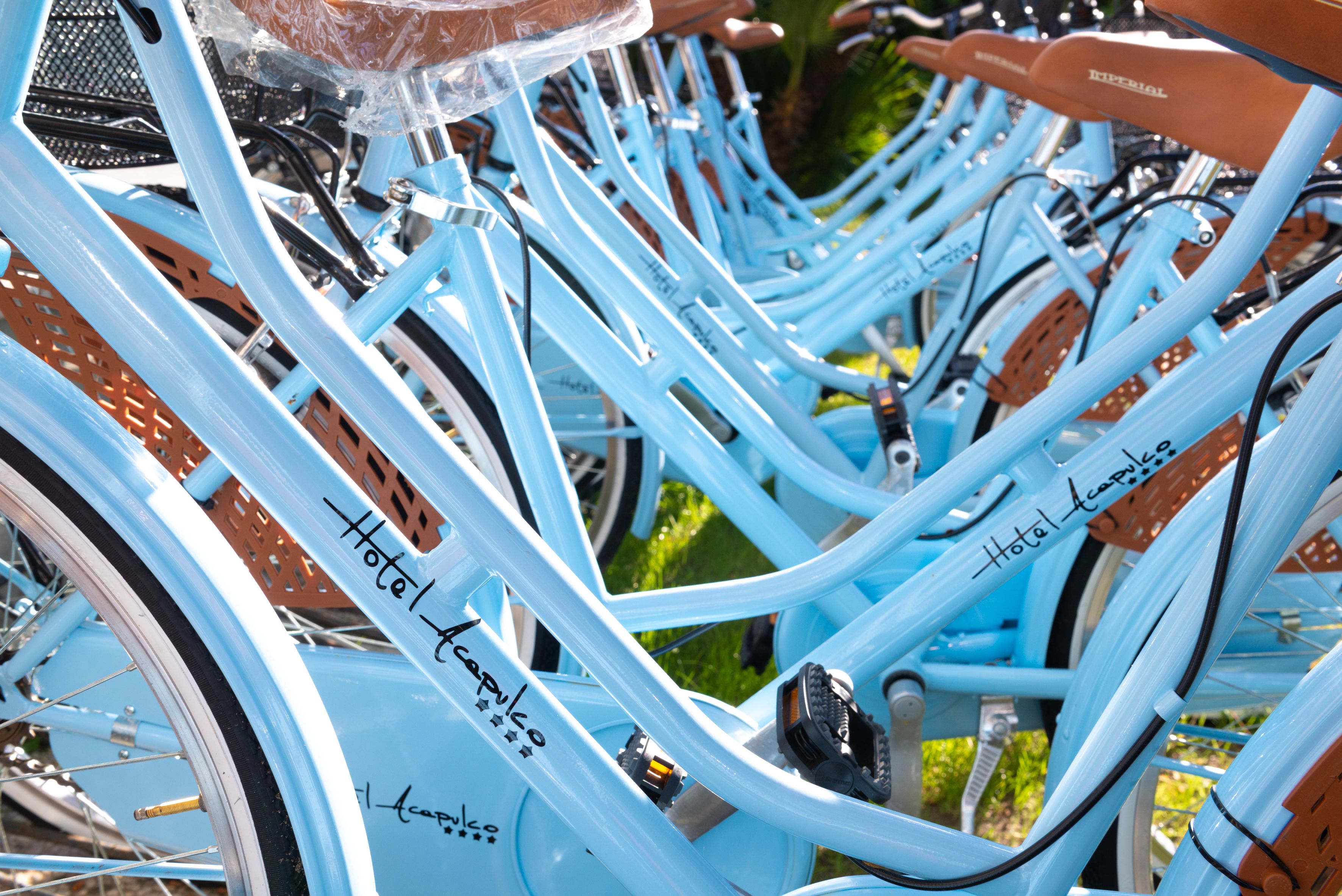 Uma fileira de bicicletas azul-claras com placas manuscritas indicando que são para uso dos hóspedes.