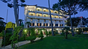Un hôtel à plusieurs étages au design moderne, doté de balcons et d’une entrée bien éclairée.