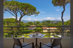 A balcony with a table, chairs, and a view of trees and buildings. - Hotel Acapulco (Forte dei Marmi)