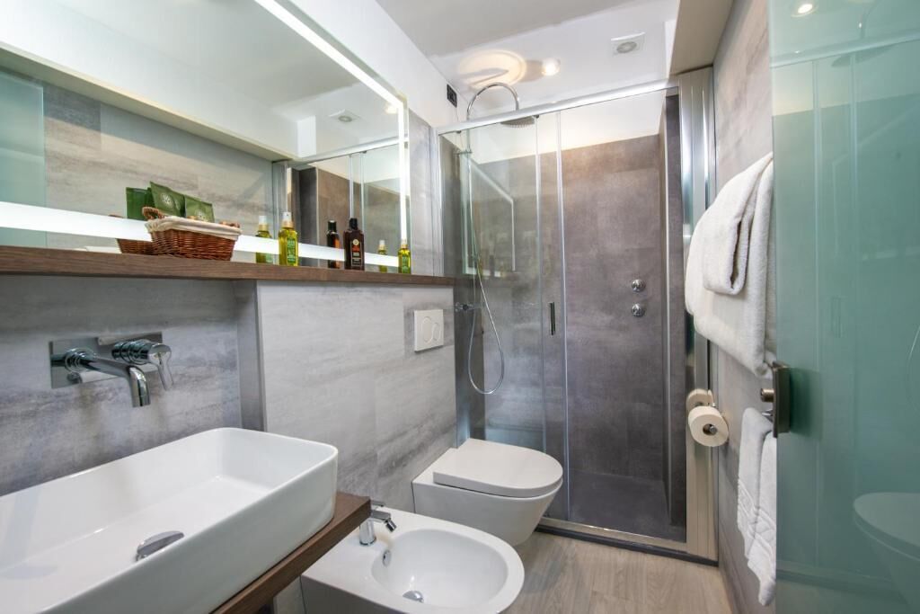 A modern bathroom with a glass shower enclosure, a freestanding sink, and a toilet.