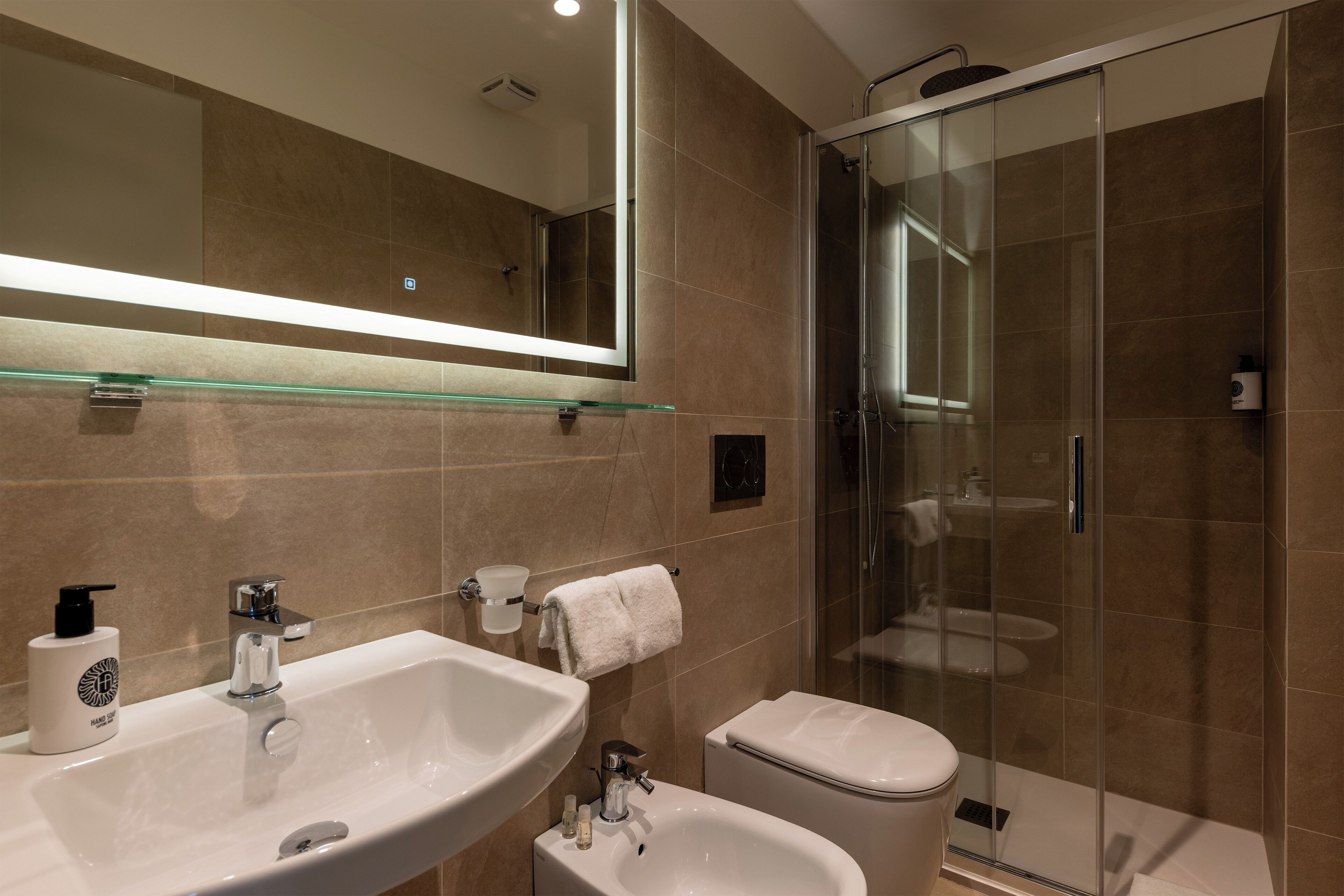Une salle de bain moderne dotée d’une douche à parois de verre, d’un grand miroir et d’un meuble-lavabo à deux vasques.