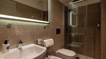 Une salle de bain moderne dotée d’une douche à parois de verre, d’un grand miroir et d’un meuble-lavabo à deux vasques.