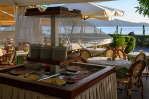 A buffet setup with various food items and a view of the sea. - Hotel Le Acacie (Capoliveri)