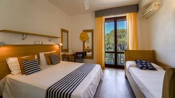 Ein Hotelzimmer mit zwei Betten, einem Deckenventilator, einer Klimaanlage, einer Uhr und Blick auf Bäume durch das Fenster.