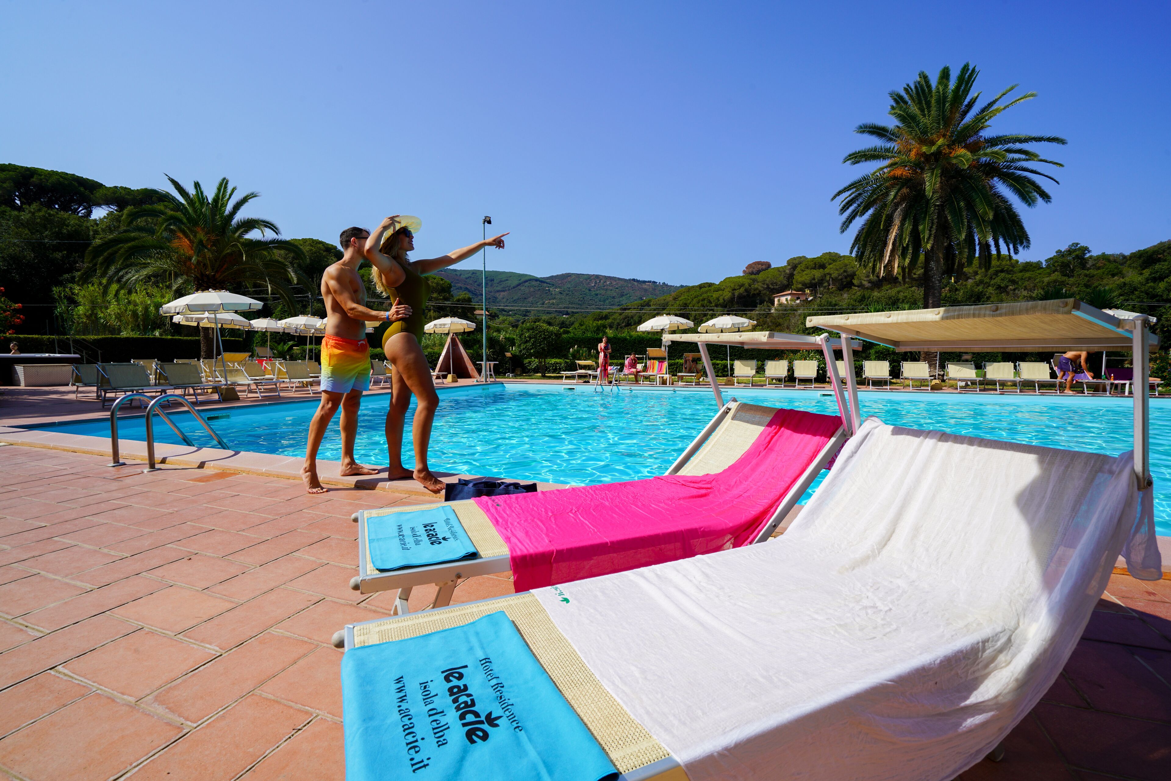 A poolside area with lounge chairs, umbrellas, and a clear view of the pool.