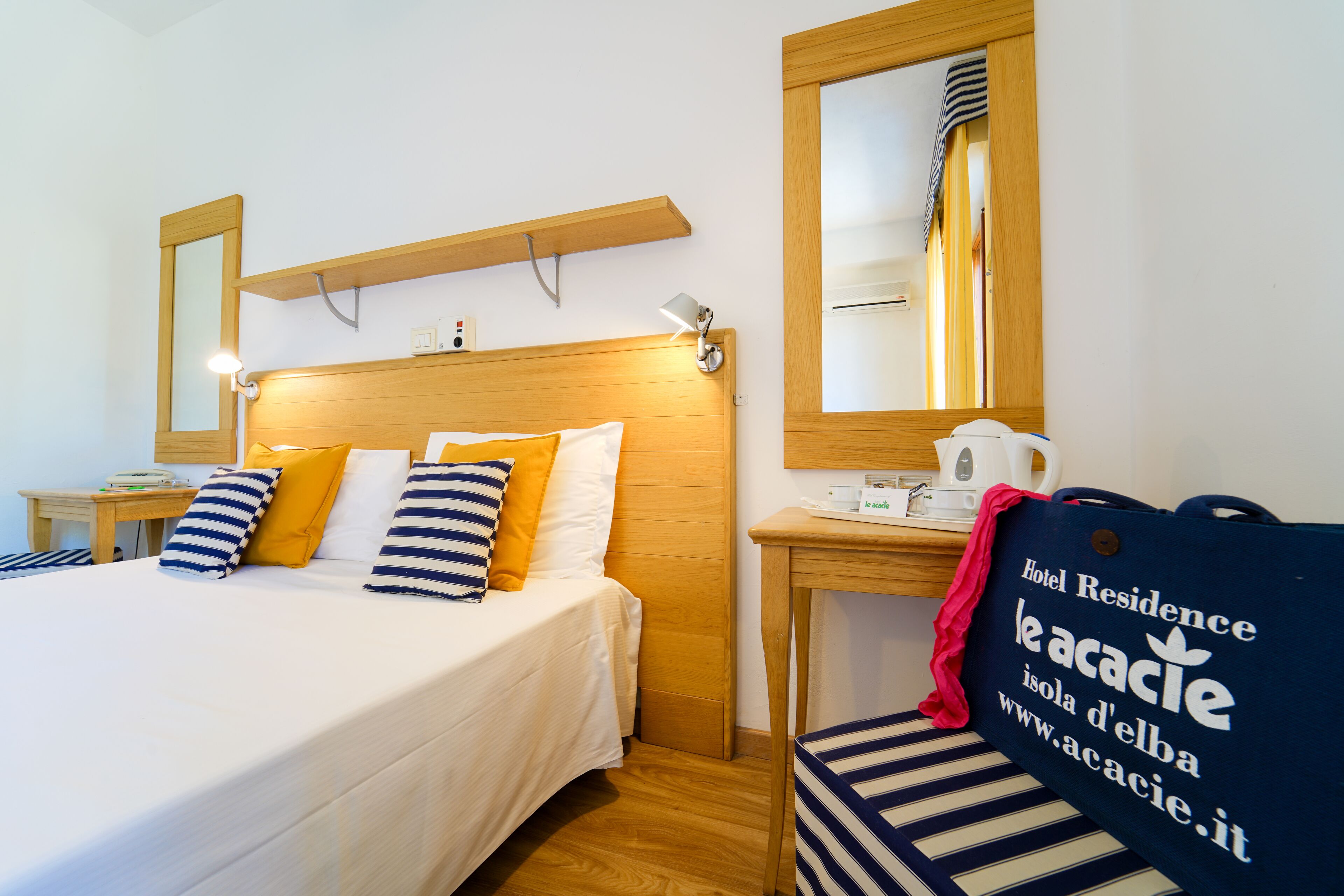 Une chambre d’hôtel avec un lit, une table de chevet, une lampe et un miroir.