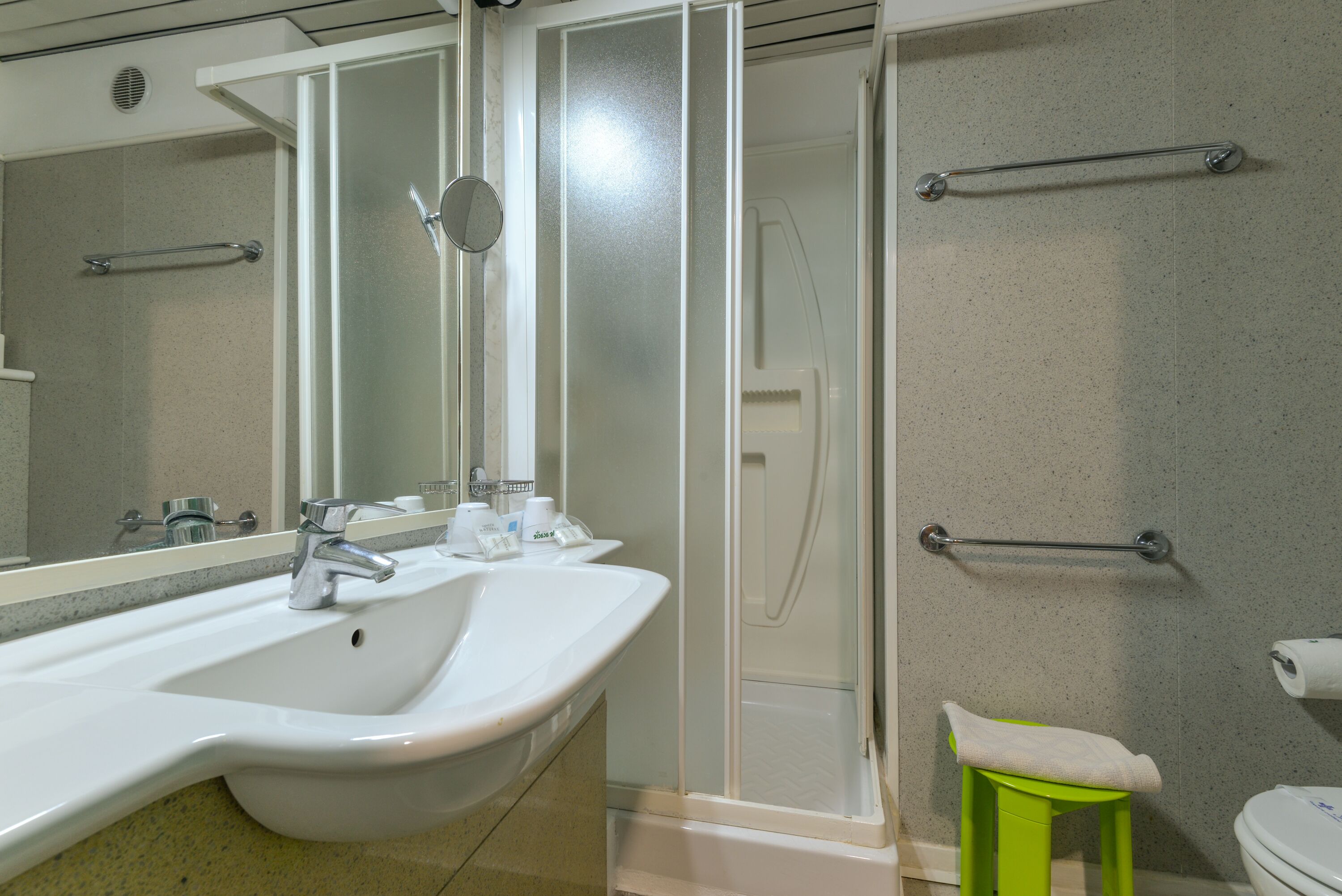 Un baño con lavabo blanco, espejo y ducha.