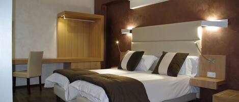 Una habitación de hotel moderna con una cama grande, mesitas de noche, un escritorio y una silla.