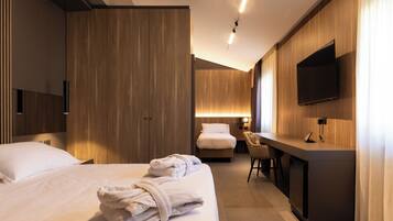 Una habitación de hotel moderna con una cama grande, un escritorio, una silla y un televisor fijado a la pared.