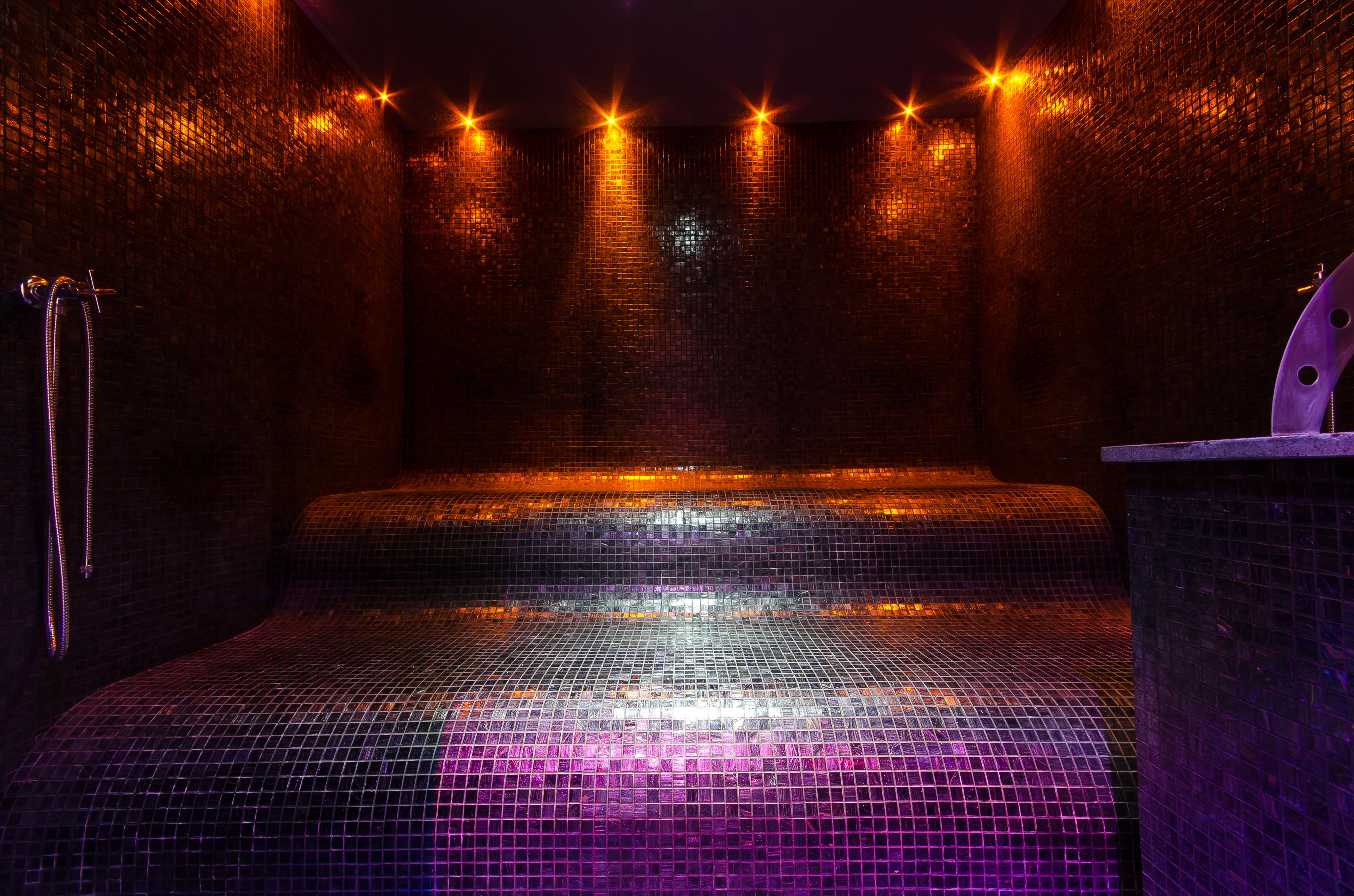 Ein schwach beleuchteter Raum mit Fliesenboden, einer Bank und einem Wandheizkörper.
