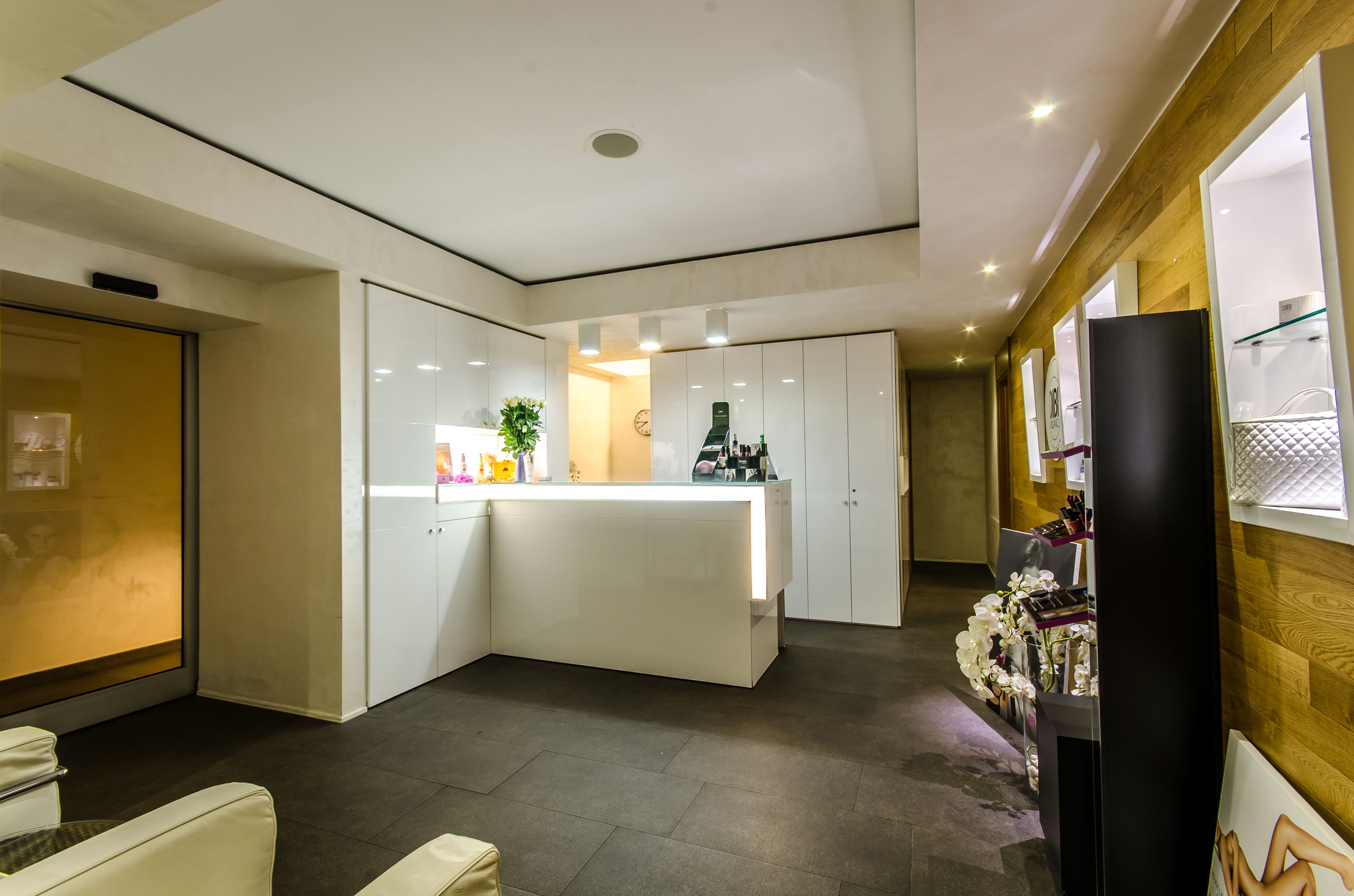 A modern hotel lobby with a reception desk, white walls, and a wooden accent wall.