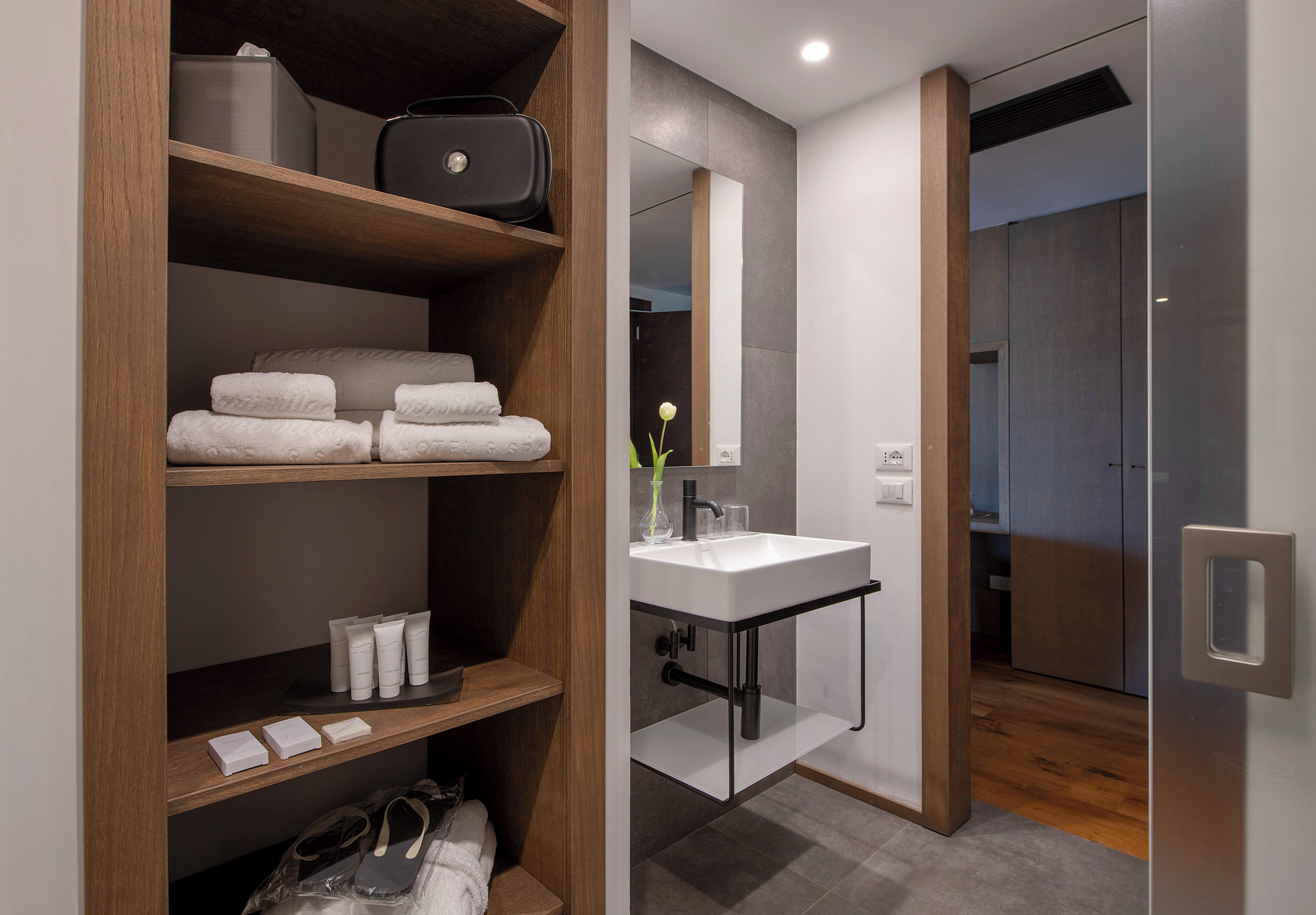 A modern bathroom with a wooden vanity, a glass shower enclosure, and a mirror above the sink.